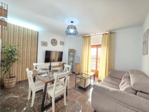 Salón moderno y luminoso con sofá, TV y zona de comedor en Apartamentos El Sagrario Jaén