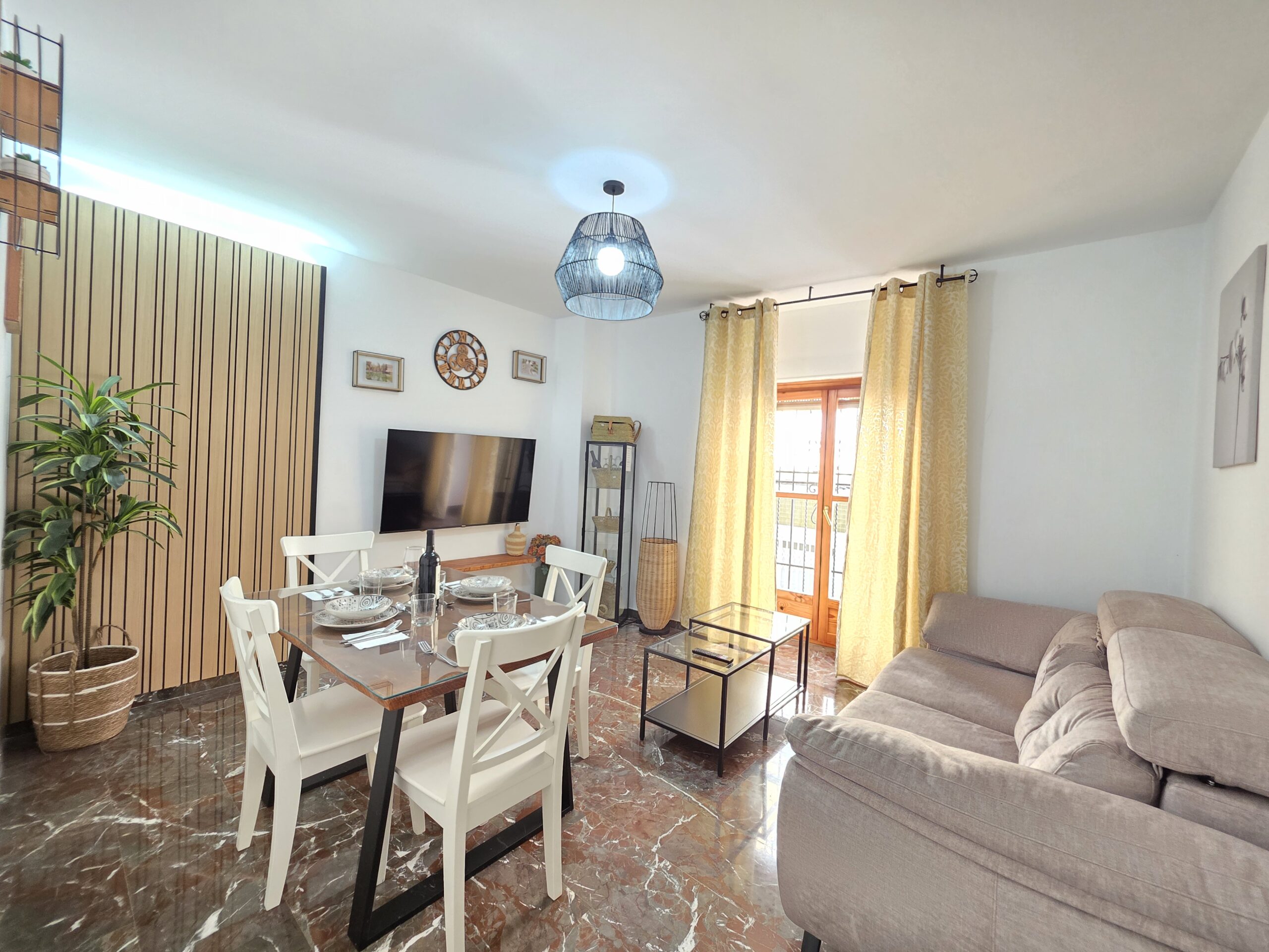 Salón moderno y luminoso con sofá, TV y zona de comedor en Apartamentos El Sagrario Jaén